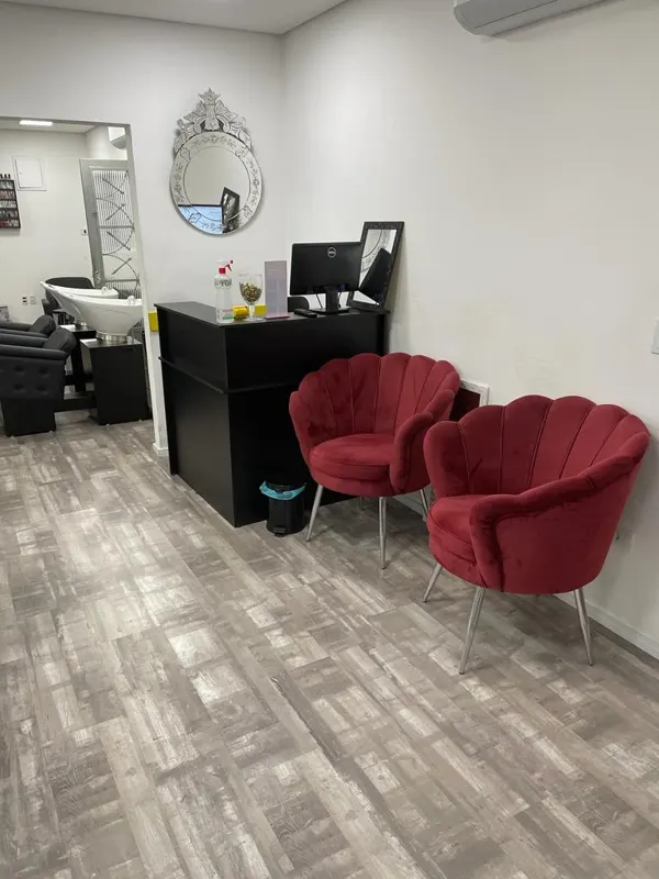 Área de espera com duas poltronas vermelhas e espelho decorativo